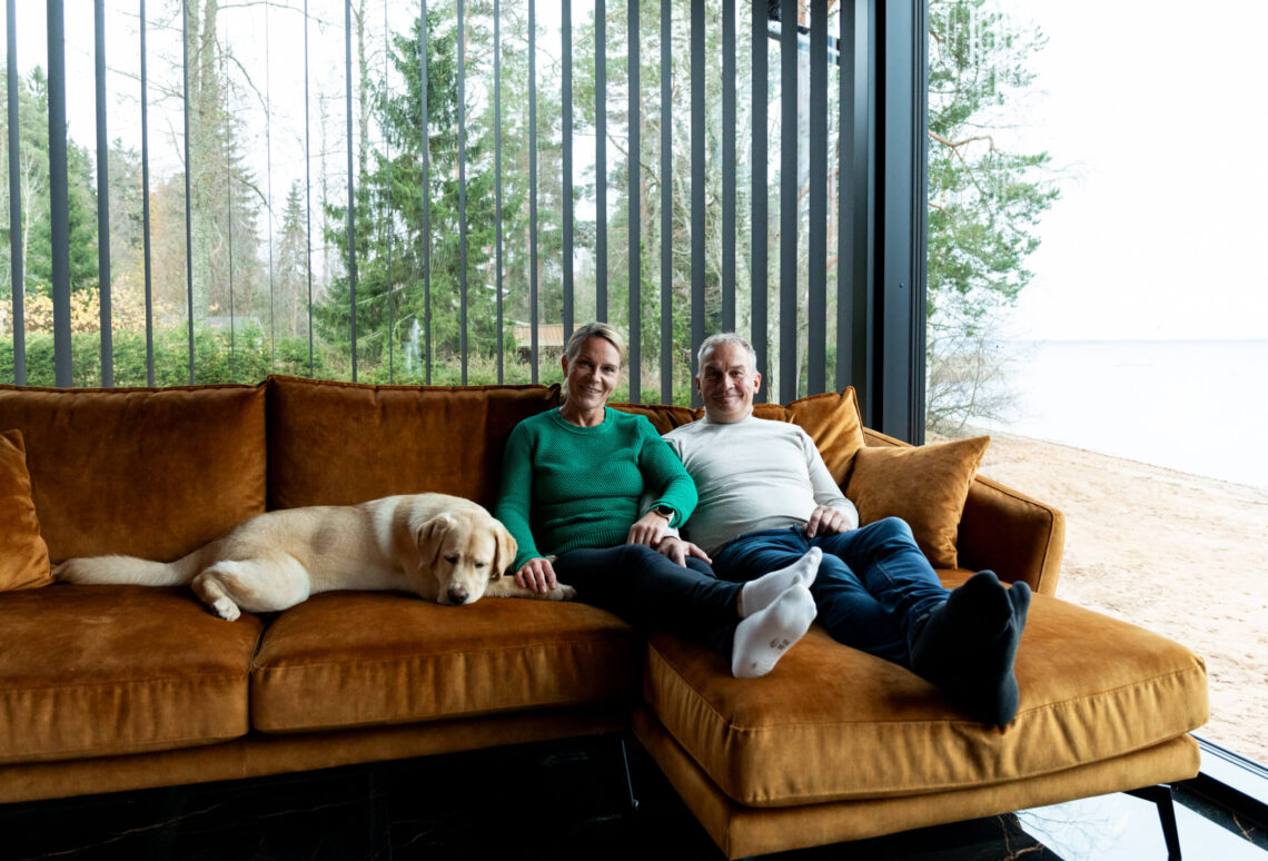 Pariskunta rentoutuu hirsitalon sohvalla